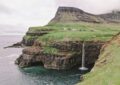 a small waterfall in the middle of a large body of water